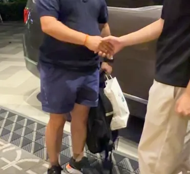 Close crop of two people shaking hands beside a vehicle